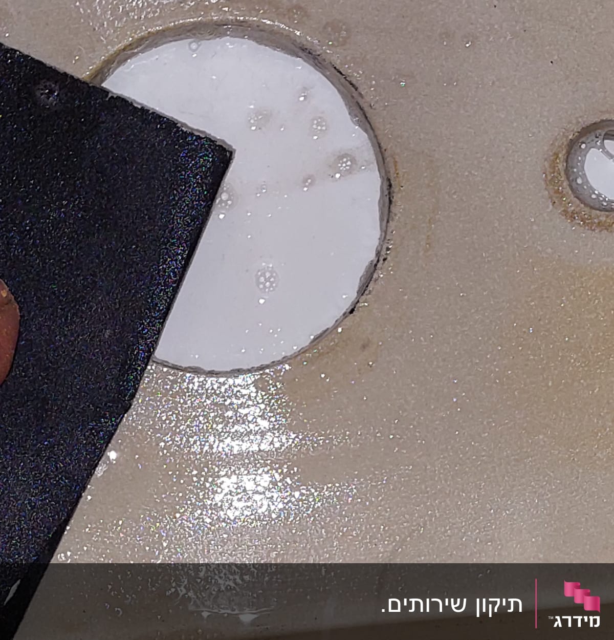 חומר איטום לבן סביב חור בכיור